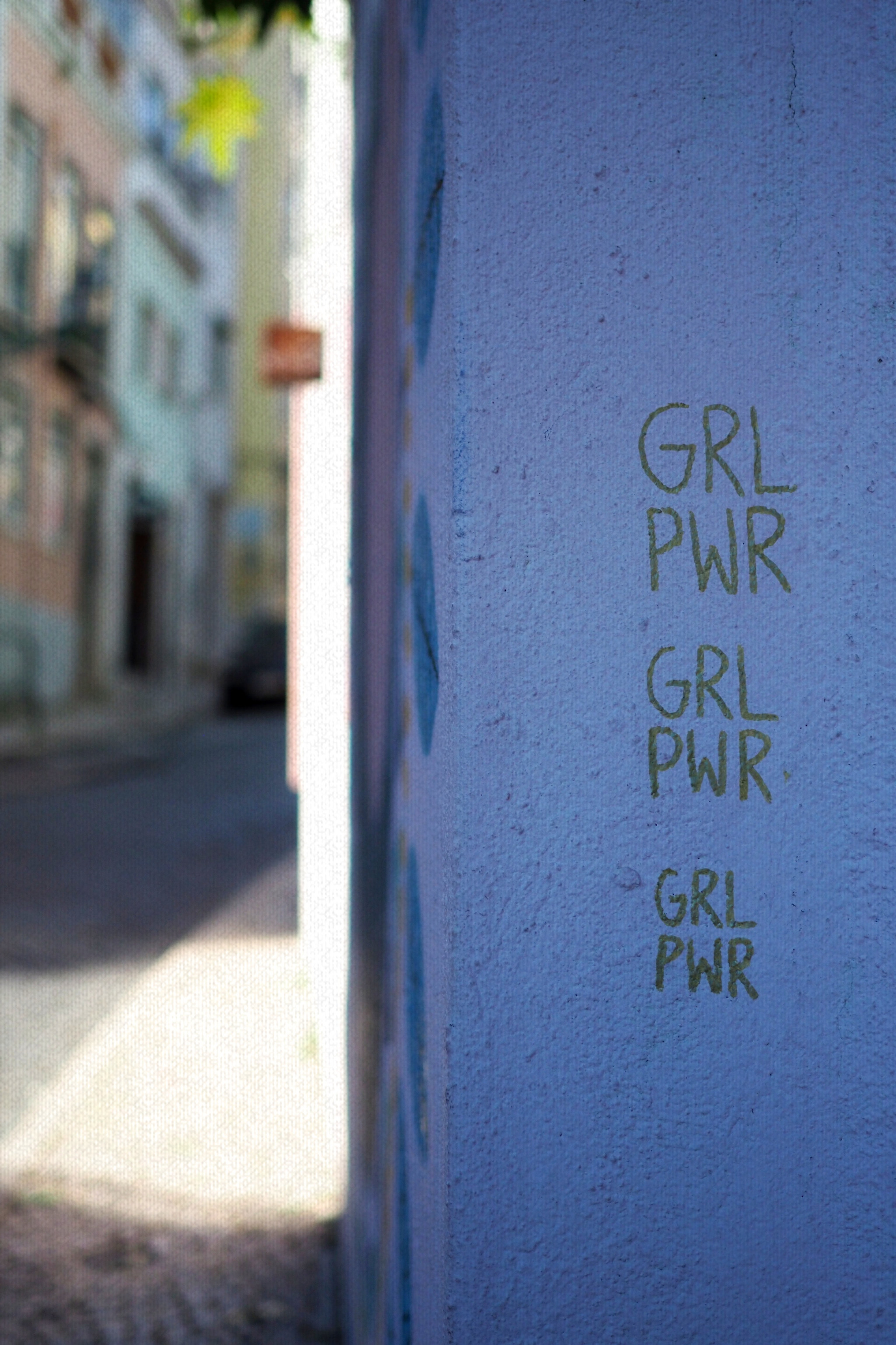 Auf einer Hauswand steht drei Mal untereinander "GRL PWR" (Girl Power)